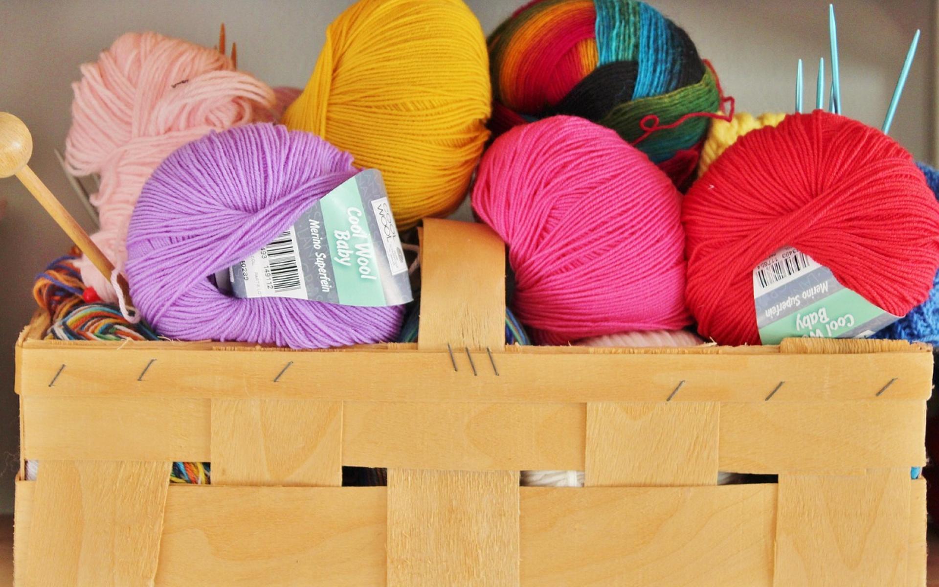 Korb mit bunter Wolle und verschiedenen Nadeln